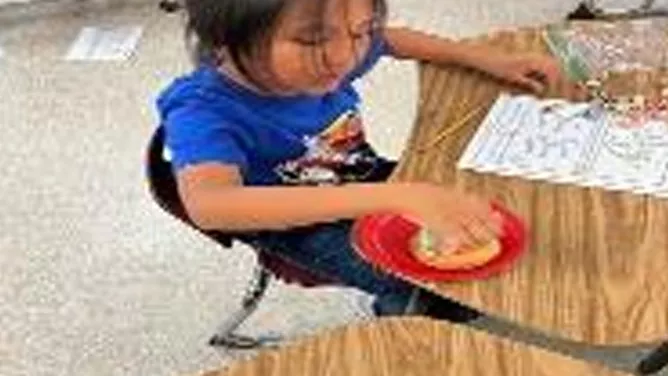 Young student playing educational games on a wooden school desk.