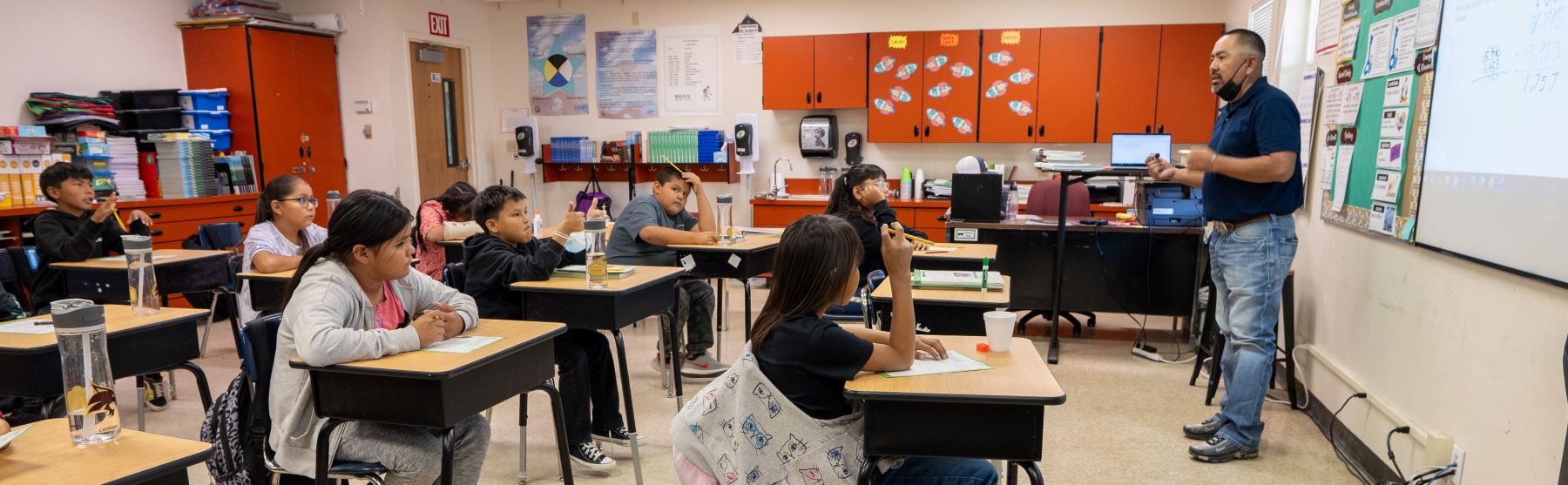 teacher in front of class of students sitting at their desks