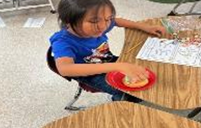 Young student playing educational games on a wooden school desk.