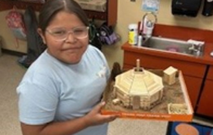 Student displaying a detailed cultural building model