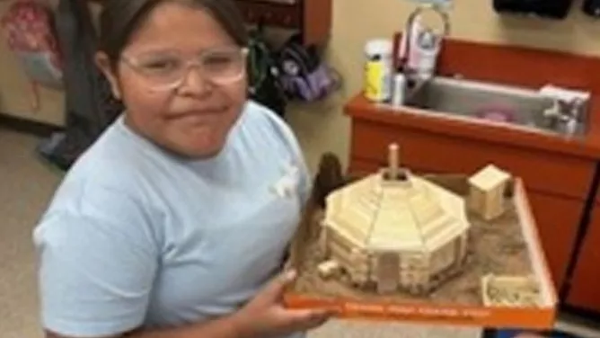 Student displaying a detailed cultural building model